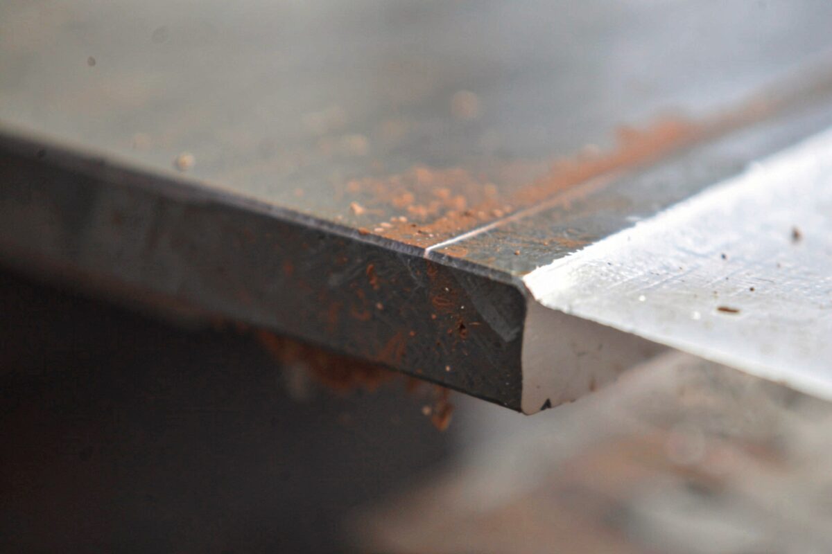 A close view of a plasma-cut edge on a steel plate showing the cut line and slight bevel.